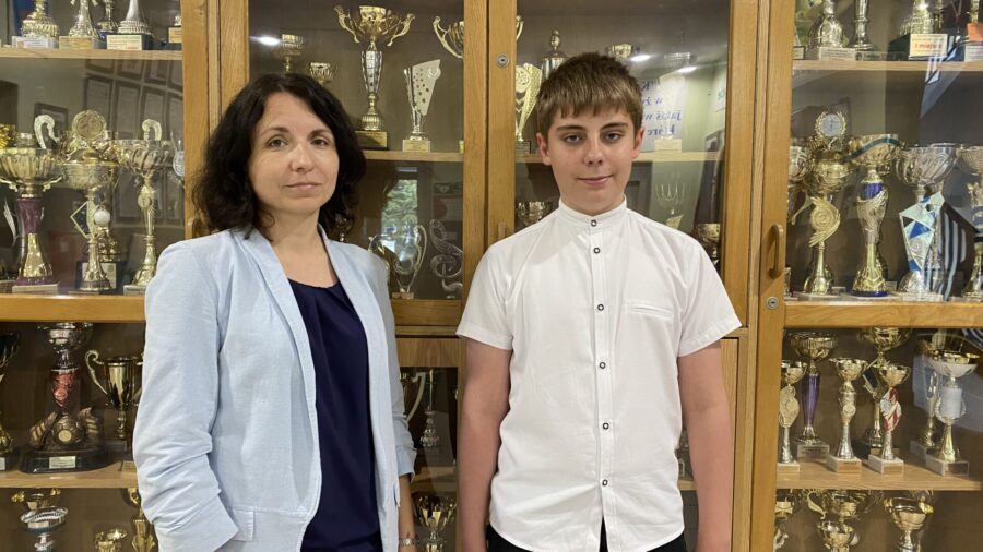 nauczycielka z uczniem na tle pucharów w szkole