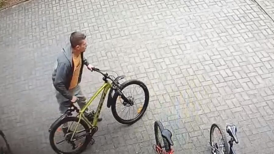 mężczyzna w szarej bluzie przy rowerze